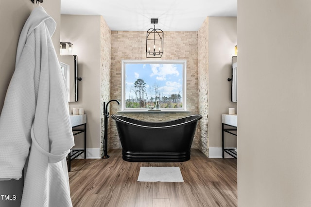 full bathroom with vanity, a freestanding tub, a notable chandelier, and wood finished floors