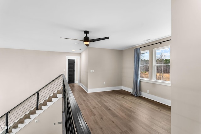 unfurnished room featuring ceiling fan, visible vents, baseboards, and wood finished floors