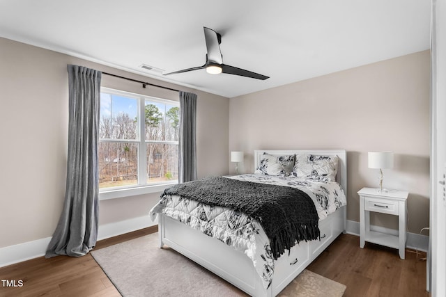 bedroom featuring ceiling fan, wood finished floors, visible vents, and baseboards