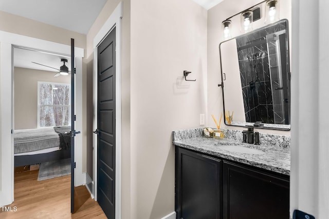 full bath featuring vanity, wood finished floors, baseboards, ceiling fan, and ensuite bathroom