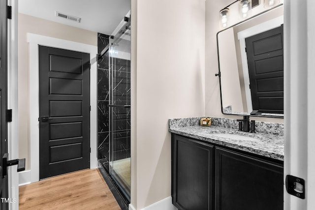 full bathroom featuring visible vents, a shower stall, baseboards, wood finished floors, and vanity