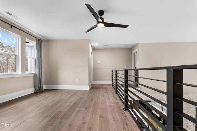 empty room featuring baseboards, visible vents, light wood finished floors, attic access, and ceiling fan