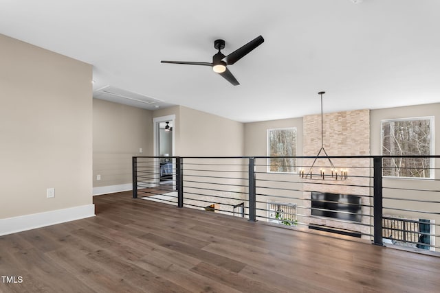 unfurnished room featuring wood finished floors, ceiling fan with notable chandelier, and baseboards