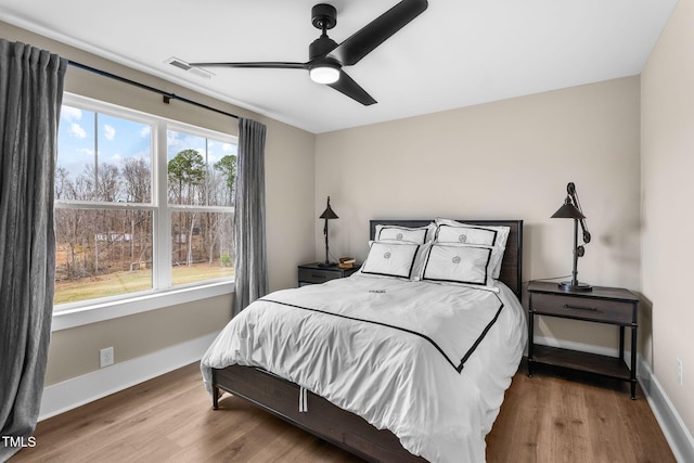 bedroom with visible vents, ceiling fan, baseboards, and wood finished floors