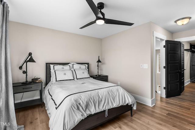 bedroom featuring ceiling fan, baseboards, and wood finished floors