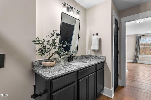 bathroom with baseboards, wood finished floors, and vanity