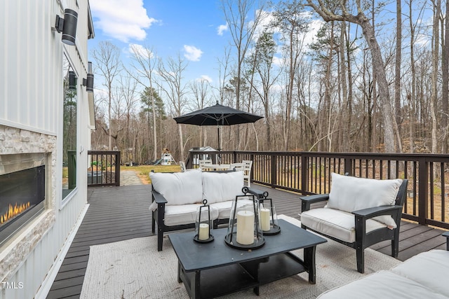 wooden terrace with an outdoor living space with a fireplace