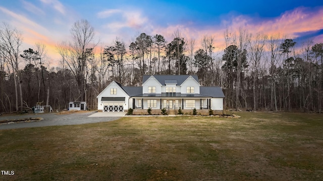 view of front of home with driveway, a front lawn, covered porch, and an attached garage