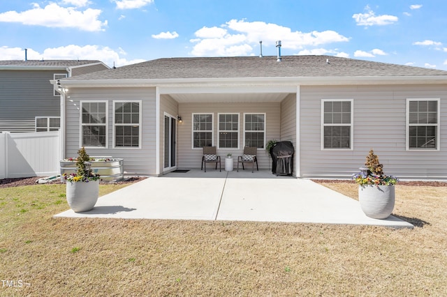 back of house with a patio, a lawn, a shingled roof, and fence