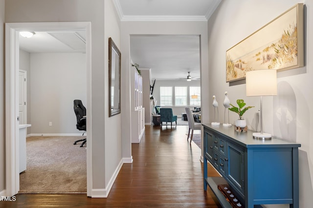 hall with crown molding, dark wood-style floors, baseboards, and dark colored carpet