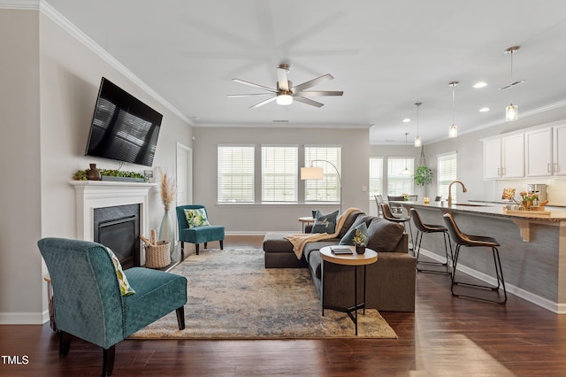 living area with ceiling fan, dark wood-style floors, visible vents, and ornamental molding