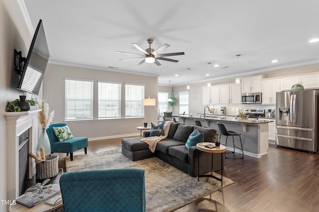 living room with a fireplace, dark wood-type flooring, a ceiling fan, and ornamental molding