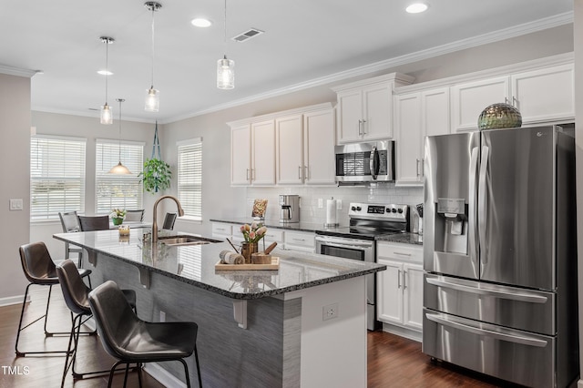 kitchen featuring visible vents, a sink, crown molding, appliances with stainless steel finishes, and a kitchen island with sink