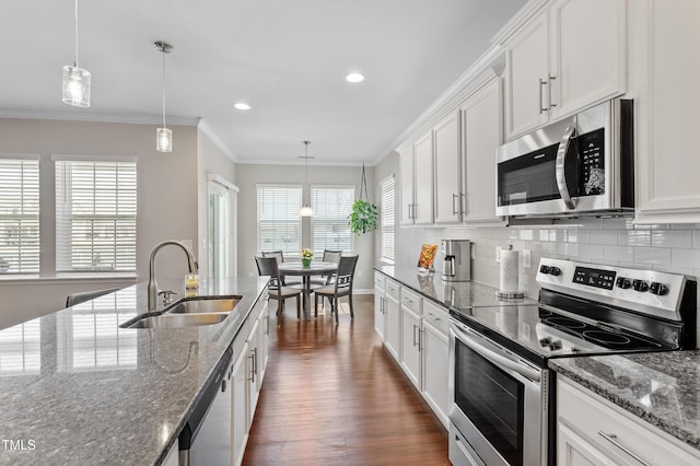 kitchen with backsplash, appliances with stainless steel finishes, crown molding, and a sink