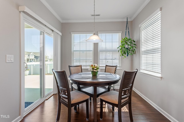 dining room featuring crown molding, dark wood-style floors, visible vents, and baseboards