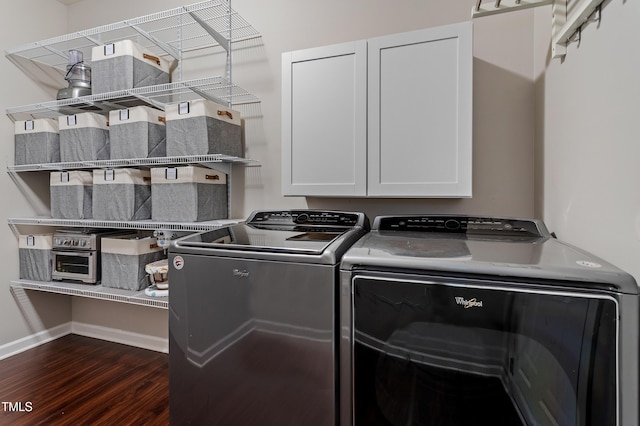 clothes washing area with baseboards, cabinet space, dark wood-style flooring, and washing machine and clothes dryer