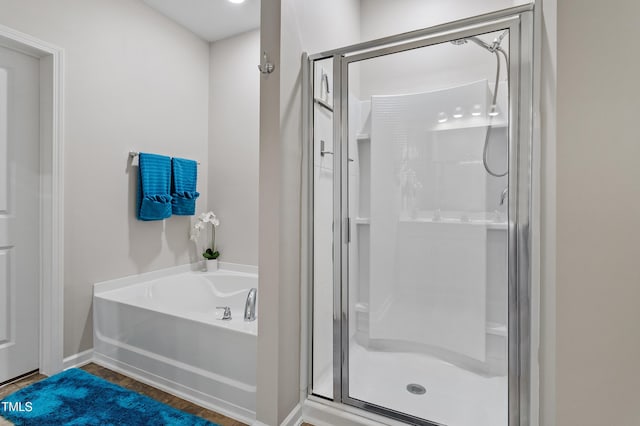 bathroom featuring a shower stall, a garden tub, and wood finished floors