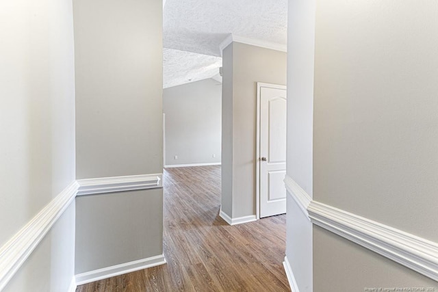 hallway featuring crown molding, wood finished floors, baseboards, and a textured ceiling