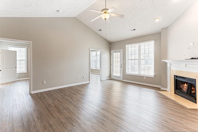 unfurnished living room featuring visible vents, a ceiling fan, wood finished floors, a premium fireplace, and baseboards