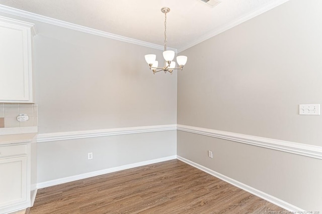 unfurnished dining area featuring baseboards, a notable chandelier, crown molding, and light wood finished floors