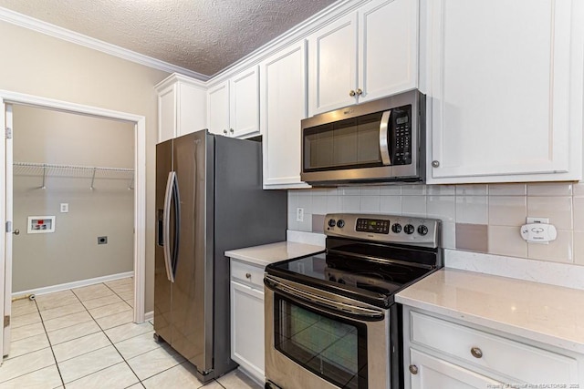 kitchen featuring a textured ceiling, tasteful backsplash, white cabinetry, stainless steel appliances, and light tile patterned floors