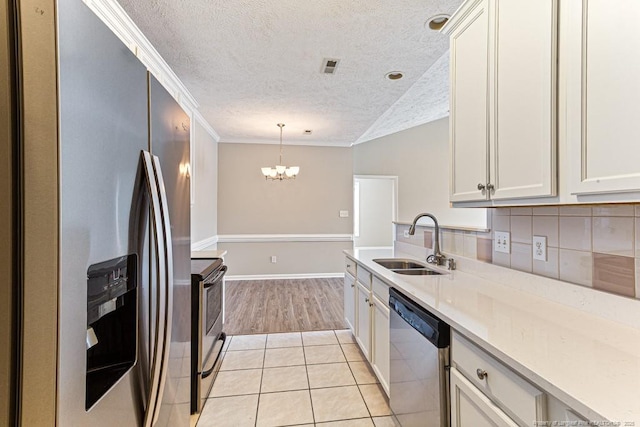 kitchen with a sink, stainless steel appliances, light countertops, crown molding, and a notable chandelier