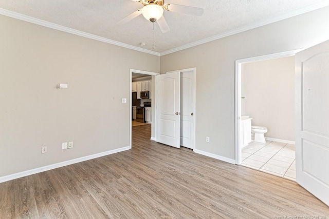 unfurnished bedroom with wood finished floors, connected bathroom, crown molding, baseboards, and ceiling fan