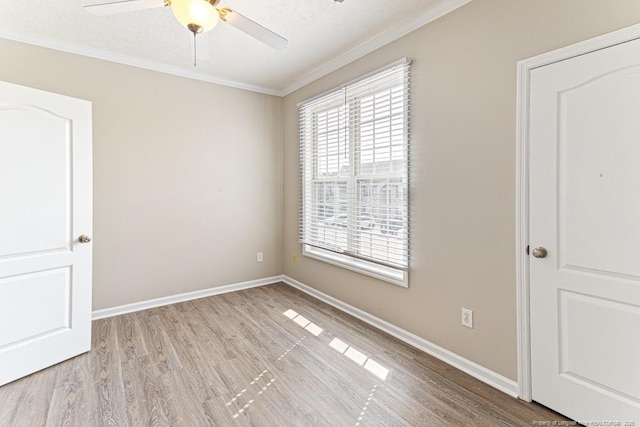 unfurnished room featuring crown molding, wood finished floors, a ceiling fan, and baseboards