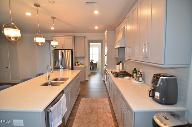 kitchen with ornamental molding, appliances with stainless steel finishes, custom range hood, and a sink