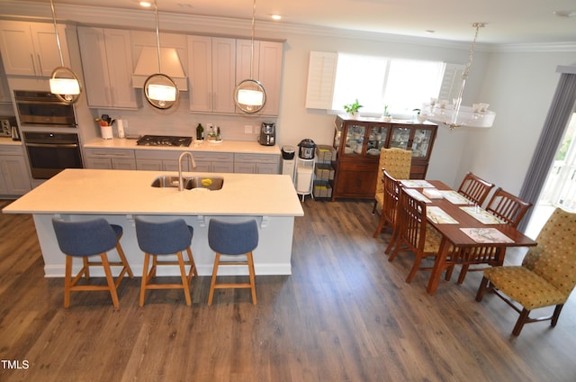 kitchen with dark wood-type flooring, a sink, gas cooktop, crown molding, and light countertops