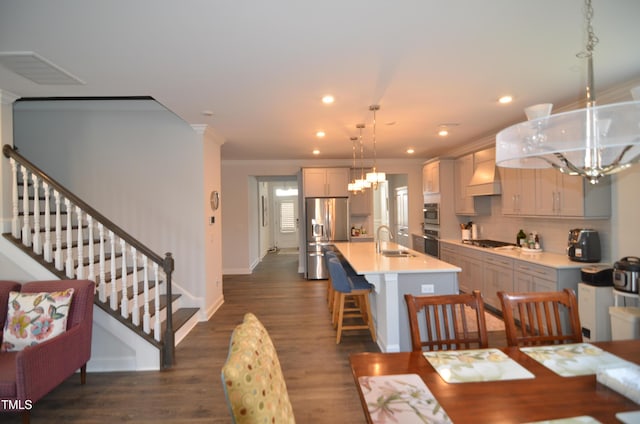 dining space with ornamental molding, dark wood finished floors, recessed lighting, stairway, and a chandelier