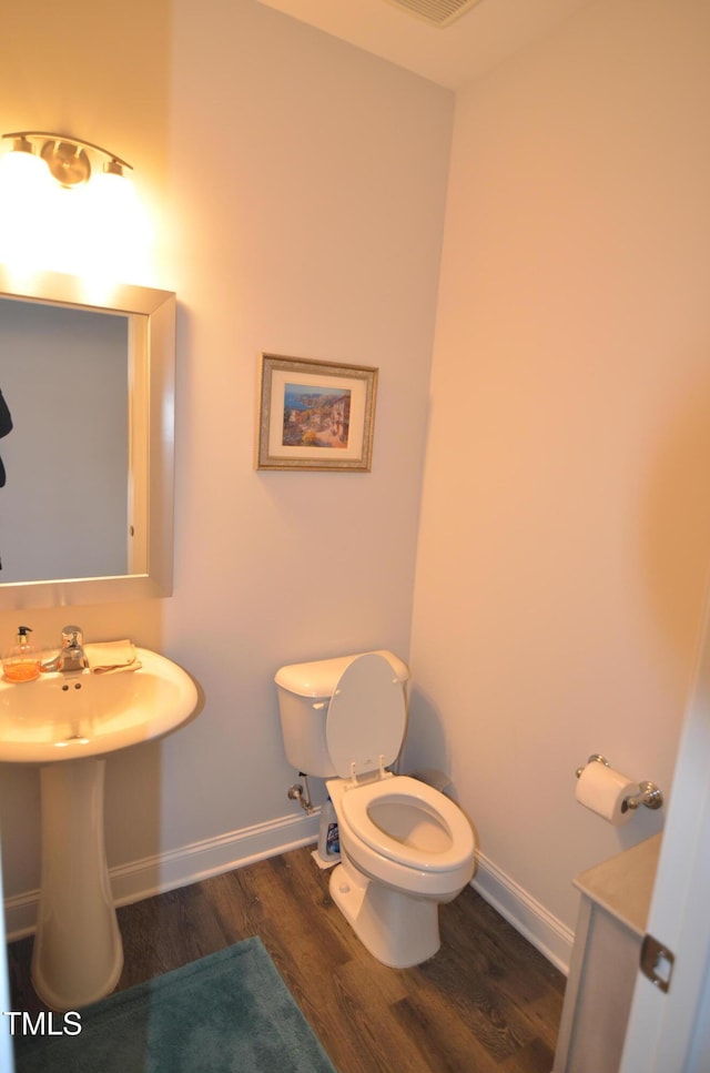 bathroom with a sink, toilet, baseboards, and wood finished floors