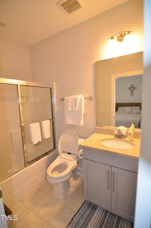 ensuite bathroom with vanity, visible vents, enclosed tub / shower combo, tile patterned floors, and toilet