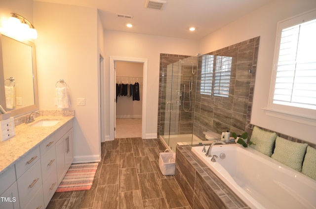 bathroom with vanity, visible vents, a stall shower, a walk in closet, and a garden tub