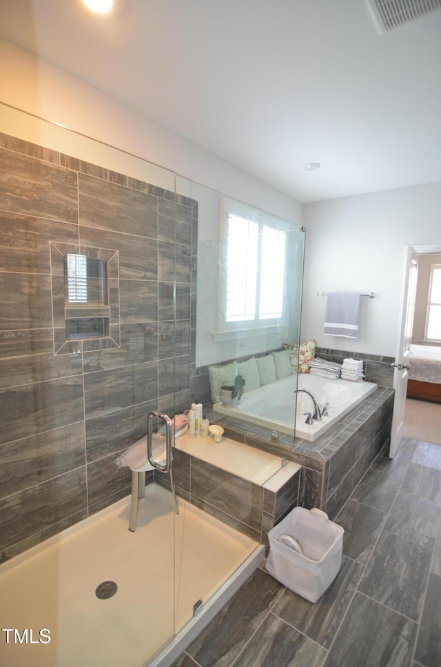 full bathroom with plenty of natural light, a garden tub, a shower stall, and visible vents