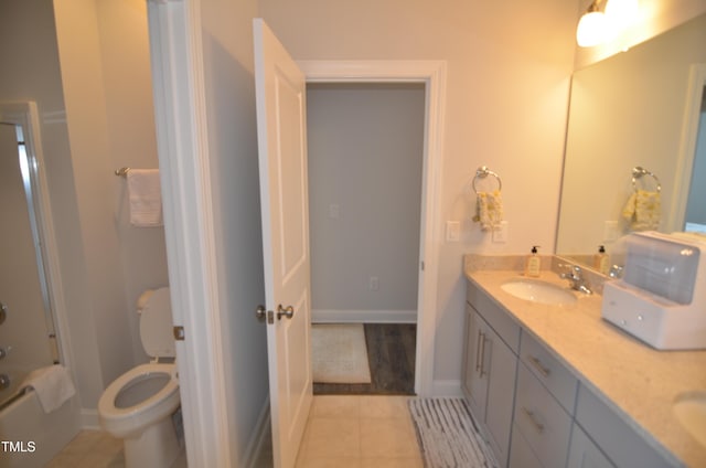 bathroom with baseboards, toilet, double vanity, tile patterned floors, and a sink