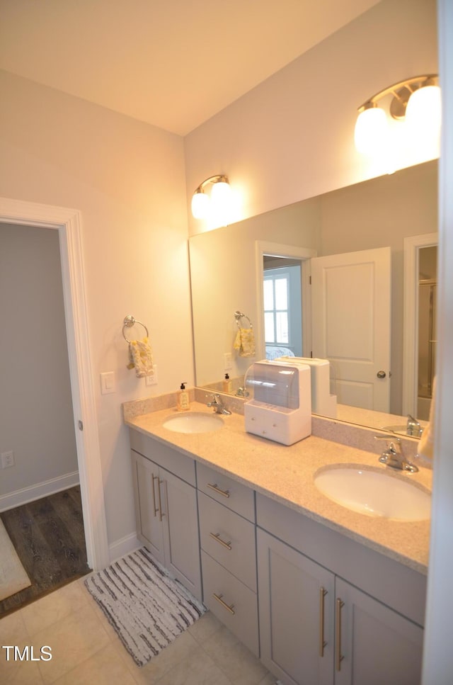 bathroom with a sink, baseboards, double vanity, and tile patterned flooring