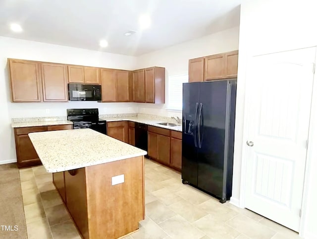 kitchen with black appliances, a sink, light stone counters, a kitchen island, and recessed lighting