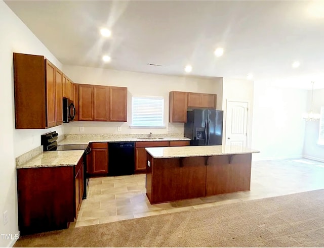 kitchen with a kitchen bar, black appliances, a sink, a center island, and light stone countertops