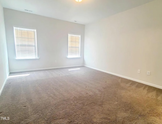 carpeted spare room with visible vents and baseboards