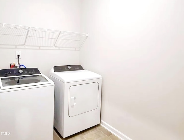 clothes washing area featuring washer and clothes dryer, laundry area, baseboards, and light tile patterned flooring