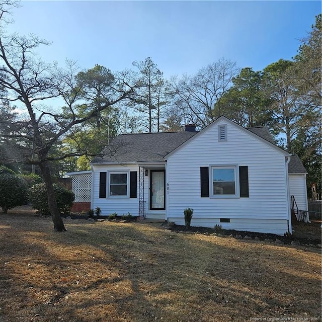 view of front of home featuring a front lawn, a chimney, and a shingled roof