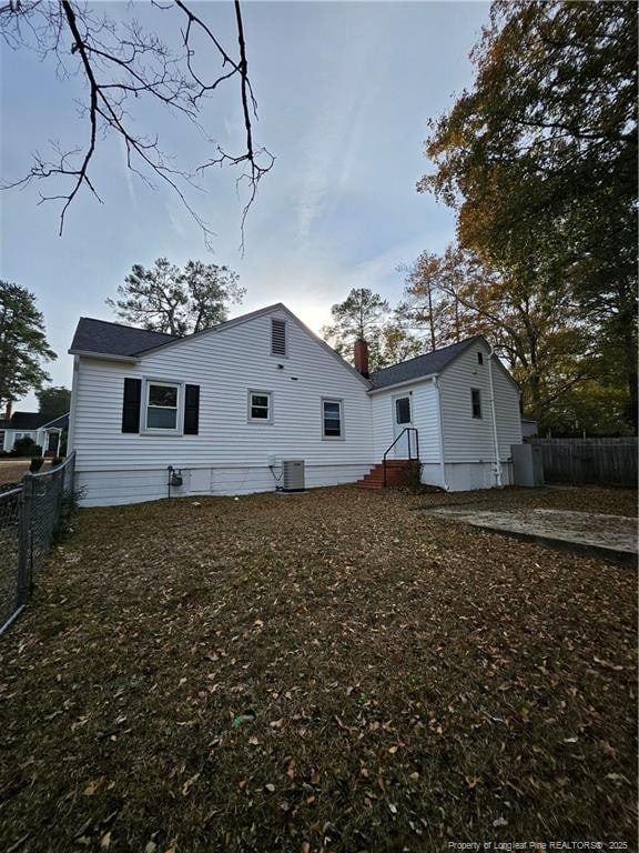 rear view of property with central air condition unit and fence