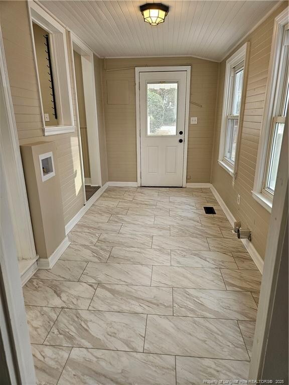 entryway with visible vents, marble finish floor, wooden walls, wooden ceiling, and baseboards