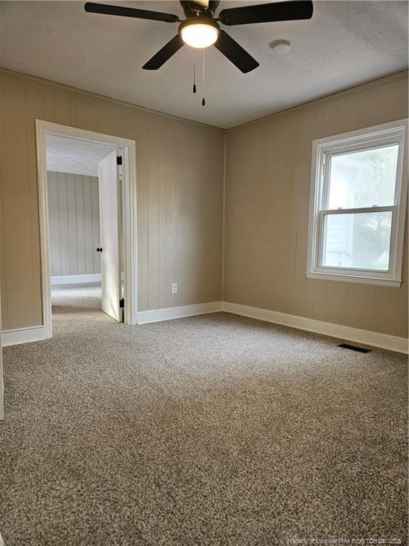 spare room featuring visible vents, a ceiling fan, a textured ceiling, carpet, and baseboards