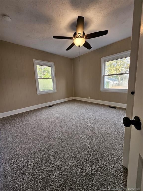 empty room featuring visible vents, a textured ceiling, and a ceiling fan