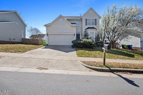 traditional-style home featuring an attached garage, concrete driveway, and fence