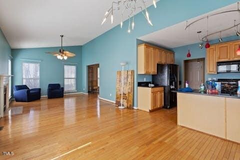 kitchen featuring dark countertops, black appliances, light wood-type flooring, high vaulted ceiling, and a ceiling fan