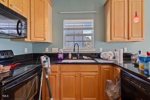 kitchen featuring black appliances, dark countertops, and a sink