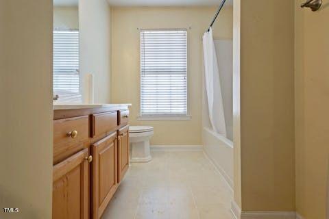 full bath with tile patterned floors, toilet, shower / bath combo, baseboards, and vanity